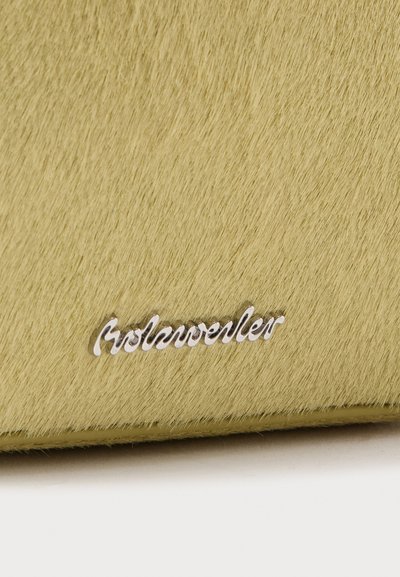 Μαλακή υφή σε ανοιχτό κίτρινο χρώμα με ένα μικρό ασημένιο μεταλλικό λογότυπο με την επιγραφή «Rosenweller» κοντά στην κάτω άκρη.