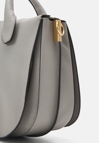 Grå läderväska med en texturerad yta, prydd med detaljer i guld och släta kanter. Designen inkluderar en semi-strukturerad form.