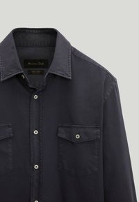 Camicia abbottonata blu scuro realizzata in tessuto intrecciato, con due tasche sul petto con chiusure a bottone e colletto classico.