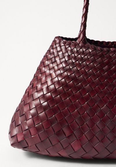 Austraukta ādas soma tumši burgundijā, ar teksturētu rakstu un izturīgām rokturiem, ar mīkstu, brīvu formu un atvērtu augšu.