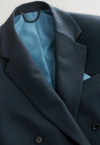 Dunkelblaues Nadelstreifen-Sakko mit glattem blauen Innenfutter, das ein doppelreihiges Design aufweist und vorne zwei schwarze Knöpfe hat.