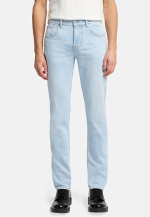 Jeans in denim blu chiaro con vestibilità slim, dotati di cinque tasche, chiusura con bottone e cuciture a contrasto. Abbinati a scarpe nere.