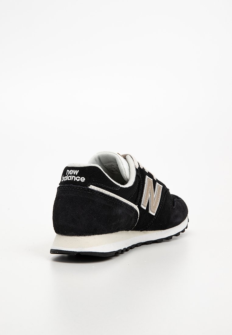 Schwarz-weiße New Balance Sneaker, schräg dargestellt, um Ferse und Seite mit Logo auf weißem Hintergrund zu zeigen.
