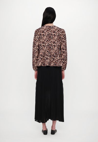 Leopard print peplum jacket in shades of brown and black paired with a long black pleated skirt. Simple black slip-on shoes.