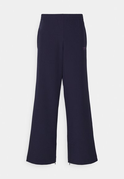 Tengerészkék, puha anyagból készült, bő szárú nadrág rugalmas derékkal és oldalsó cipzárokkal az alján, a Fontaine logójával elöl.