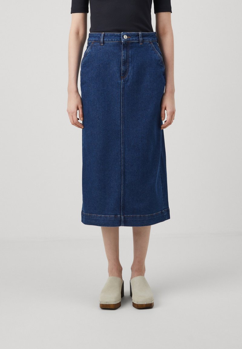 Denim midi svārki ar tumši zilu mazgājumu, taisnu griezumu, sānu kabatām, jostu cilpiņām un strukturētu apakšmalu. Saskaņoti ar bēšiem klogiem.