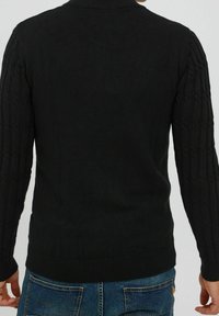 Czarny sweter dziany z prążkowanymi mankietami i teksturowanym wzorem warkoczowym na rękawach. Model wkładany przez głowę z okrągłym dekoltem.