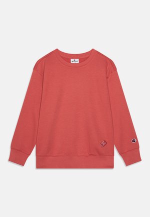 Korallrød sweatshirt laget av myk stoff, med rund hals, ribbestrikkede mansjetter, og et logo-lapp nær kanten og ermet.