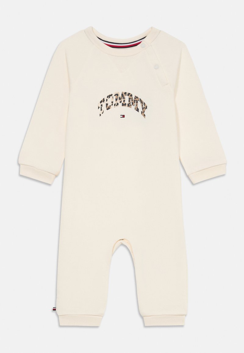 Romper de bebé de manga larga color crema con texto "Tommy" en estampado de leopardo y pequeño logo de bandera en el pecho, botones a presión en el hombro, puños acanalados.