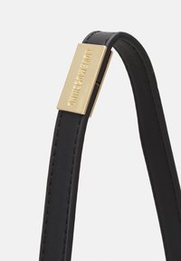 Černý kožený pásek se zlatou kovovou sponou, na které je vyryté "LOVE MOSCHINO", zdůrazňující jeho elegantní design a hladkou texturu.