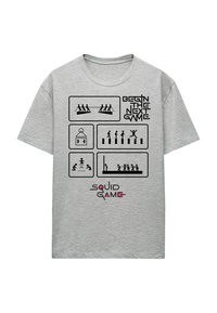 Gray cotton t-shirt featuring black graphics depicting game scenes and text "BEGIN THE NEXT GAME" and "SQUID GAME" in pink accents.