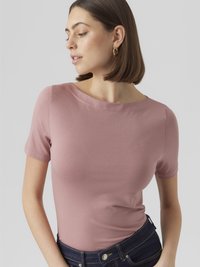 Kortermet, tettsittende topp i rosarosa, laget av glatt stoff med rund halsutringning. Kombinert med mørk denimjeans for kontrast.