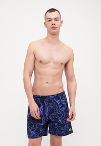 Shorts da nuoto neri con un motivo astratto blu, vita elastica e tasche laterali. Il materiale sembra leggero e liscio.