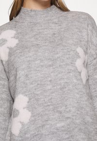 Maglione grigio lavorato a maglia con un colletto alto, decorato con morbidi motivi floreali di colore rosa chiaro sulla parte anteriore e tessuto testurizzato.