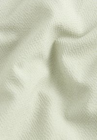Tejido de color verde claro con una textura y un patrón tejido fino; caída suave con un brillo sutil; parece transpirable y ligero.