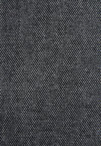 Tejido texturizado de color gris oscuro con un patrón diagonal de hilos entrelazados en gris claro y blanco, creando una apariencia de cuadros sutil.
