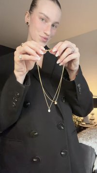 Kihiline kullavärvi kaelakee, millel on kaks kettide rida ja erineva suurusega ringikujulised ripatsid. Modell hoiab seda neutraalsel taustal.