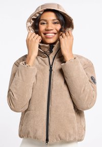 Beżowa kurtka sztruksowa z pikowanym kapturem, zamkiem błyskawicznym, elastycznymi mankietami i naszywką z logo. Posiada prążkowaną teksturę i lekko skrócony krój.