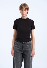 Czarny krótki rękaw dopasowany t-shirt z gładkiego materiału, w połączeniu z luźnymi spodniami dżinsowymi w ciemnoszarym kolorze z wysokim stanem, minimalistyczny design, bez widocznych logo.
