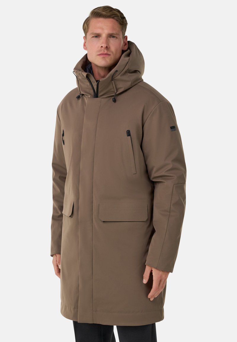 Brun vattentät parkas med huva, utrustad med blixtlåsförsedda bröstfickor och en framficka med klaff. Slät textur och knälång design.