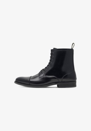 Fekete bőr boka csizma sima felülettel, kerek orral, fűzős elülső résszel és hátsó húzófüllel. Különböző varrott részletek jellemzik, alacsony sarkú.