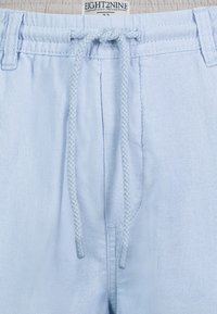 Hellblaue Leinen-Shorts mit einem geflochtenen Kordelzug, flachem Bund und seitlichen Taschen. Markenetikett oben.