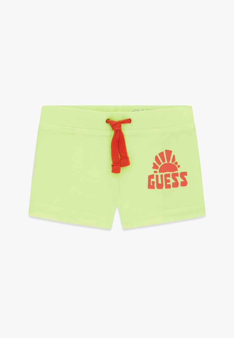 Shorts vert clair avec cordon rouge et graphique de soleil rouge avec le texte « GUESS » sur la jambe droite.