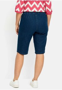 Džínové bermudy s elastickým pasem, tmavě modré barvy, s hladkou texturou a rovný střih končící těsně nad kolenem.