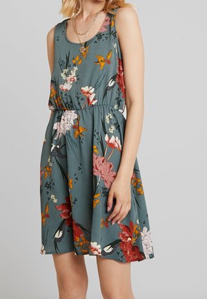 Ärmelloses Kleid in Türkis mit Mustern aus roten, rosa und orangefarbenen Blumen. Elastischer Taillenbund und fließendes Rockdesign. Weicher Stoff.