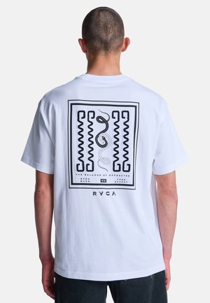 Persona vestita con T-shirt bianca con motivi geometrici astratti neri e testo sul retro: "The Balance of Opposites", "Open Mind", "Free Spirit" e "RVCA".