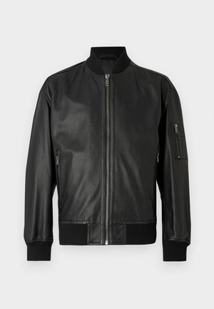 Czarna skórzana kurtka bomberka z zamkiem z przodu, ściągaczem przy kołnierzu, mankietach i dole oraz zamykaną kieszenią na lewym rękawie.