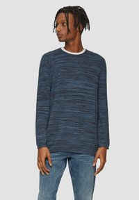 Marineblauer Pullover aus einem strukturierten Strickstoff mit langen Ärmeln und Rundhalsausschnitt. Trägt dazu hellblaue Jeans.