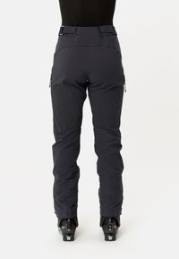 Zwarte skibroek met een hoge tailleband, zijritsen, taps toelopende pijpen en een gladde, matte afwerking. Ontworpen voor wintersporten en koud weer.