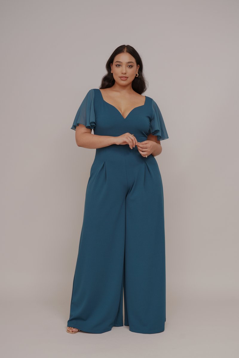 Türkisfarbener Jumpsuit mit fließenden Ärmeln, V-Ausschnitt und weitem Bein-Design. Hergestellt aus glattem Stoff mit subtilen Falten an der Taille.