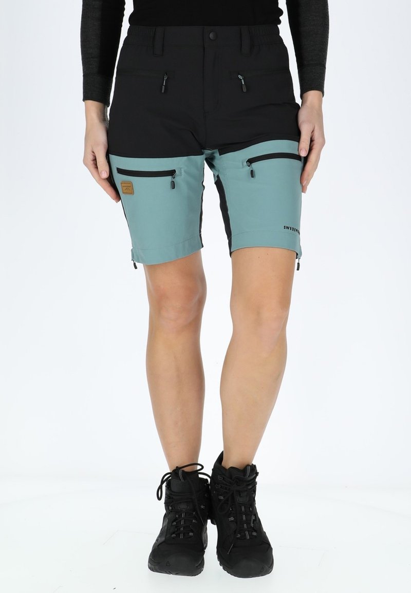 I pantaloni corti presentano una parte superiore nera, una sezione inferiore teal e molteplici tasche con zip. Realizzati in tessuto leggero con un design durevole.