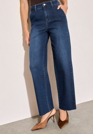 Mørkeblå højtaljede brede jeans lavet af denim med en rå kant. Parret med brune spidse slingback-hæle.