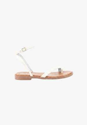 Sandalia plana con finas tiras blancas, hebilla en el tobillo y suela color piel, diseñada para uso casual.