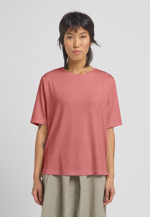 Maglietta a maniche corte, collo a girocorso in corallo, realizzata in tessuto morbido con una vestibilità rilassata e ampia. Presenta una texture liscia e un design minimale.