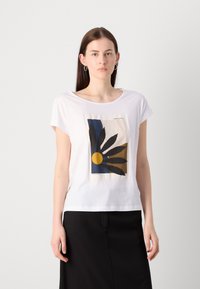T-shirt en coton blanc avec un imprimé graphique d'une fleur stylisée en bleu, jaune et noir. Manches courtes et col décontracté.