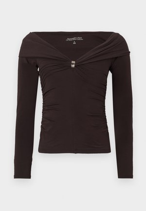 Langärmlige, schulterfreie Bluse aus dunkelbraunem Stoff, mit einem gerafften Design und einem silbernen Akzent in der Mitte vorne.
