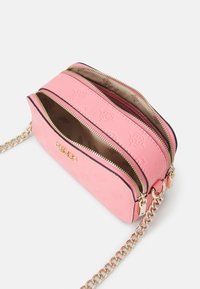 Lyserød læder crossbody taske med gyldne lynlåse, præget mønster, gyldent logo og gylden kædestrosse, vist let åben på hvid baggrund.