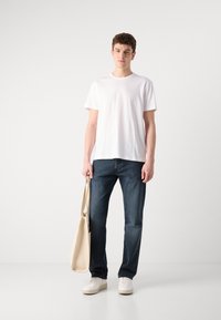 White short-sleeve t-shirt, dark blue jeans, beige tote bag, white sneakers. Simple, relaxed fit, smooth fabric, clean design.