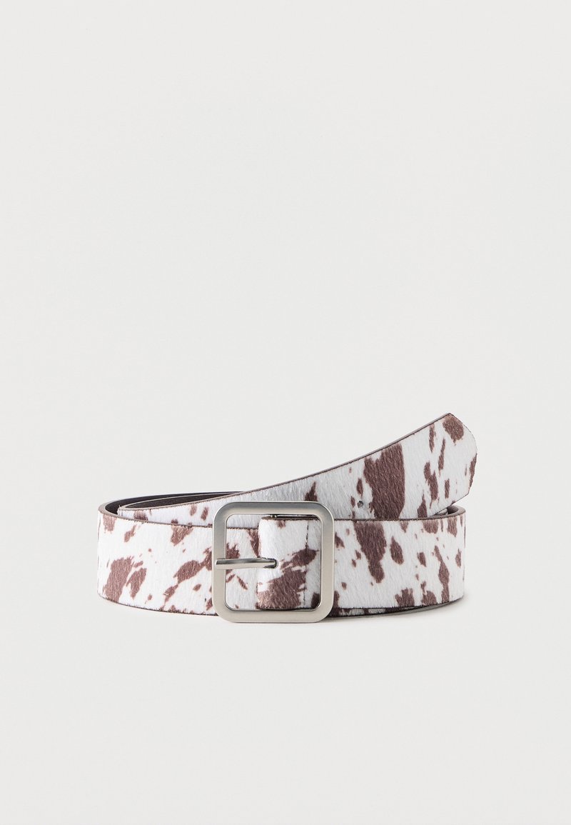 Ζώνη με τύπωμα αγελάδας σε λευκό και καφέ χρώμα με ασημένια ορθογώνια αγκράφα, τυλιγμένη σε απλό ανοιχτό φόντο.