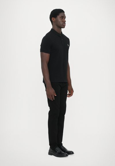Black polo shirt with short sleeves and a collar, paired with black slim-fit pants and black shoes, set against a neutral background.