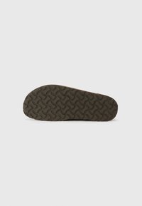 Brown shoe outsole with a textured pattern featuring wavy lines and circular accents. Rubber material designed for grip and durability.