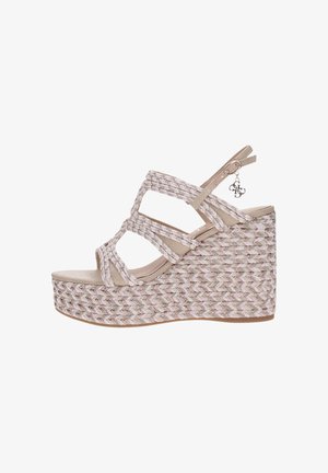 Sandalia de cuña beige tejida con tres tiras trenzadas, hebilla trasera y adorno decorativo, con tacón plataforma y diseño de punta abierta.