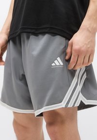 Γκρι αθλητικές βερμούδες από ελαφρύ ύφασμα, με λευκές διχτυωτές λεπτομέρειες και λογότυπο στο πλάι. Διαθέτουν ελαστική μέση για άνεση.