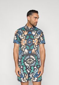 Πουκάμισο με κοντά μανίκια και κουμπιά και σορτς, με πολύχρωμο αφηρημένο ανθικό μοτίβο σε σκοτεινό φόντο. Κατασκευασμένα από ελαφρύ ύφασμα.