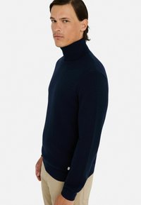 Granatowy sweter z golfem, wykonany z miękkiego materiału dzianinowego, z prążkowanymi mankietami i dołem. Dopasowany krój z gładką fakturą, minimalne detale brandingowe.