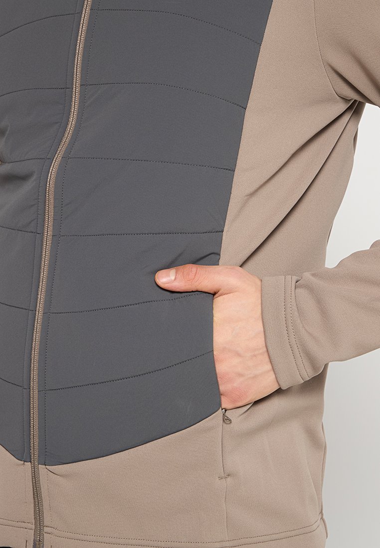 Lekka kurtka z zamkiem z przodu, szary, pikowany panel na klatce piersiowej z poziomymi przeszyciami oraz beżowa dolna część z bocznymi kieszeniami.